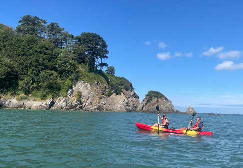 two people in a double kayak, kayaking in the sea in North Devon